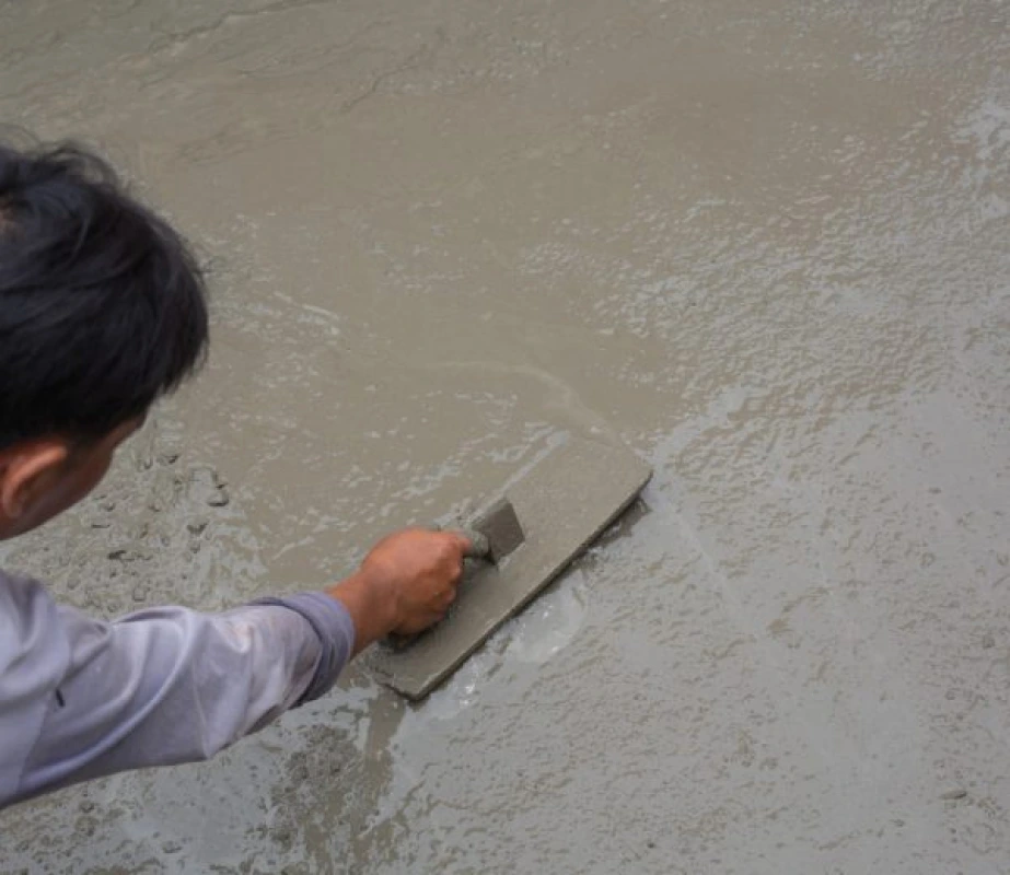 masonry contractor using a trowel to smooth freshly poured wet concrete